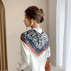 Elegant paisley square silk scarf in navy and caramel draped over shoulder for spring