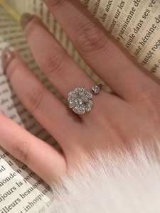 Detail of flower shaped open ring with micro-set zircons on vintage book background