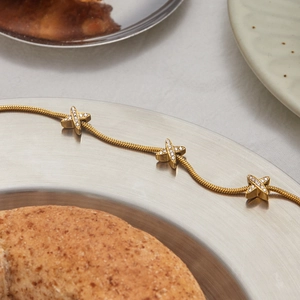 Dettaglio del bracciale a catena serpente in acciaio placcato oro 18K con ciondoli X