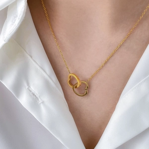 Close-up of interlocking double heart pendant in polished gold on an elegant O-chain necklace