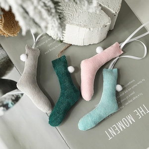 Set of 4 knitted Christmas stockings with pompoms in pastel tones for festive holiday decor