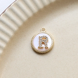 Macro shot of letter R gold-plated shell pendant with inlaid cubic zirconia and bead edge