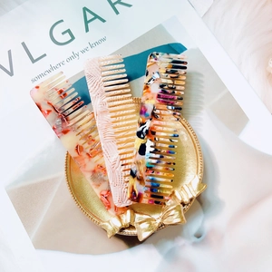 Detailed view of three marble-patterned acetate hair combs on a golden tray display
