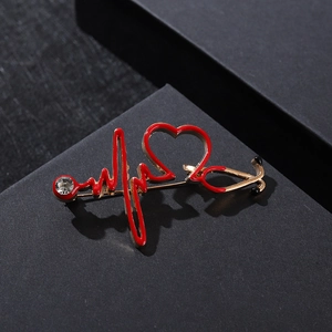 Detailed macro view of heart-shaped stethoscope brooch with red enamel and crystal