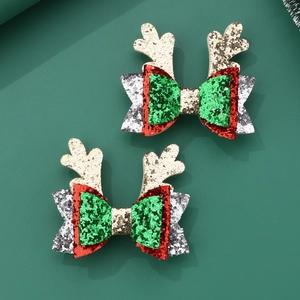 Detail of glitter Christmas bow hair clips with reindeer antlers on green background