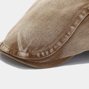 Close-up of vintage brown washed denim fabric and double stitching on the short brim cap