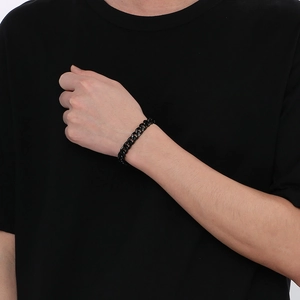 Close-up of a black titanium steel Cuban link bracelet on a male model wrist