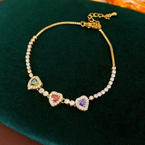 Detail of 18k gold plated bracelet featuring colorful heart stones on green velvet