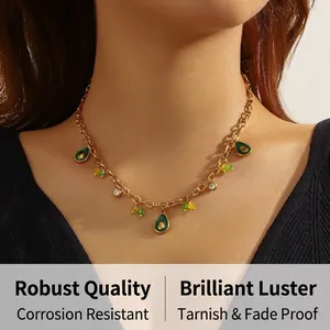 Gros plan du collier doré avec pendentif avocat vert et détails en strass brillants
