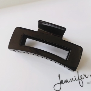 Close-up of a 10.5cm glossy black rectangular hair claw clip on a white display card