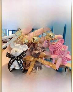 Detailed view of woven resin bear keychains in pink, brown, and white with gold bell charms