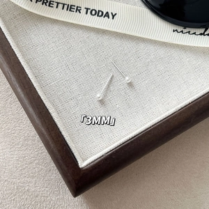 Macro view of 3mm pearl stud earrings on light fabric showing the minimalist silver pins