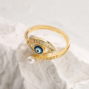 Detail of gold evil eye ring with blue enamel, white zircon stones and pearl accent
