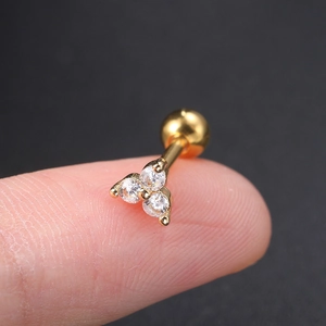 Mini-Ohrknorpelstecker aus Gold mit drei weißen Zirkonia, auf einer Fingerspitze gezeigt