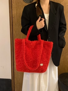 Dettaglio borsa shopper in peluche rosso con ciondolo a cuore e manici su modella