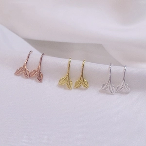 Three pairs of elegant leaf earrings in rose gold, gold, and silver on white silk fabric