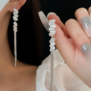 Close-up of silver tassel earrings with rectangular crystals showing movement and shine