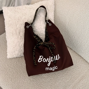 Detail of dark brown canvas tote bag with leopard print bow and Bonjour magic print