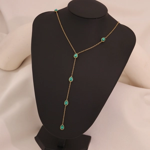 Golden Y-shaped necklace with turquoise teardrop gemstones on a black mannequin display