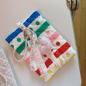 Détail d'une trousse à maquillage matelassée avec chaîne en perles et charme brodé