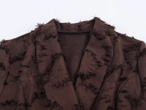 Detail eines braunen Jacquard-Blazerkleides mit Fransenstoff und scharfem Revers-Design