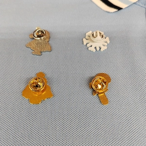 Detail view of four Christmas pins with metal butterfly backings on blue fabric
