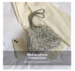 Macro view of silver sequin bucket bag size comparison with a smartphone on beige fabric