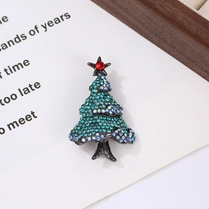 Macro shot of a Christmas tree brooch with teal and iridescent rhinestones on a metal base