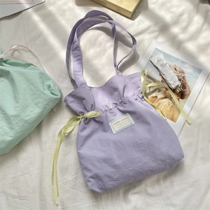 Detail of purple drawstring canvas tote with yellow ribbon and Sorahke Studio label