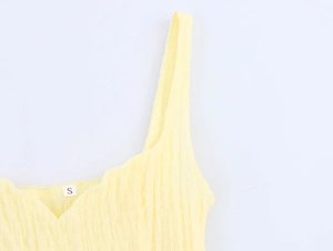 Close-up of yellow textured fabric straps and neckline detail with size S label