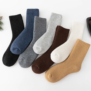 Flat lay of seven pairs of thick wool crew socks in assorted neutral winter colors