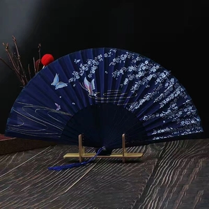 Close-up of dark blue folding fan with silver floral patterns and blue tassel on stand