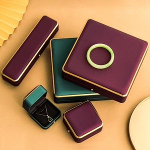 Deep purple and emerald green silk jewelry boxes with gold metal edges and ribbon bow detail