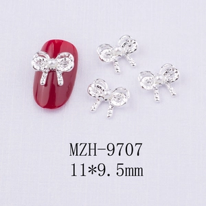 Détail de bijoux d'ongles en forme de nœud argenté avec perle et taille 11x9,5 mm