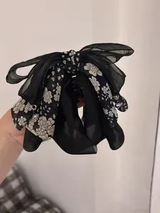 Close-up of black chiffon bow hair claw clip with floral fabric and small metal beads