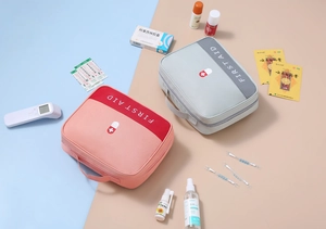 Top view of portable first aid kit bags with handles and medical items on a neat surface