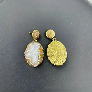 Detail of baroque pearl earrings with gold lava texture and sparkling crystals