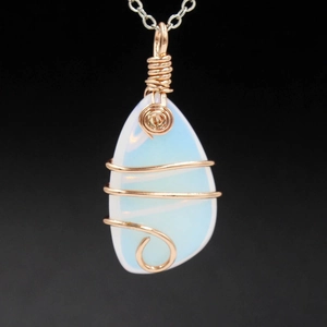 Opal stone pendant necklace with rose gold wire wrap on a black background