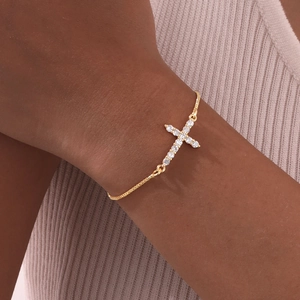 Detail of a gold-plated box chain bracelet with a sparkling zircon cross on a wrist