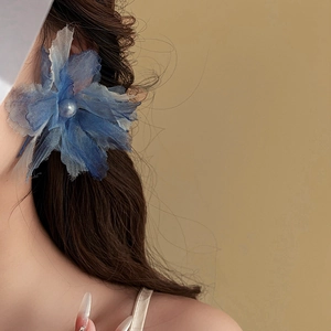 Blue fabric flower hair clip with pearl center accessory worn on model's hair