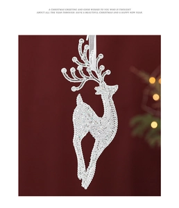 Close-up of a silver glitter reindeer ornament with white ribbon on red background