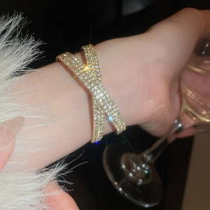 Détail d'un luxueux bracelet croisé en X doré avec pavé de diamants étincelants sur le poignet