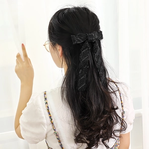 Elegant handcrafted black bead-embroidered bow hair clip worn on long wavy hair