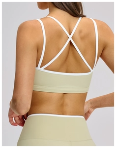 Detail of sage green sports bra showing criss-cross back straps and white piping