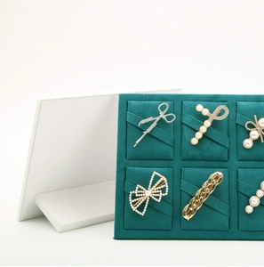 Detail of golden hair clips with pearls on a dark green velvet display board
