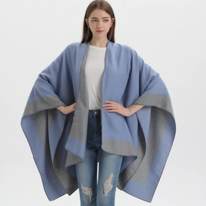 Detail view of a loose knit poncho cape with elegant blue and grey contrast trimming