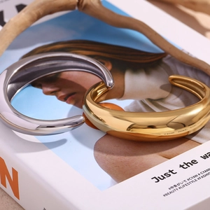Polished gold and silver wide open bangles displayed on a stylish fashion magazine
