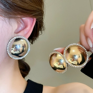 Macro detail of glossy gold round stud earrings with shimmering crystal border