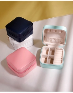 Macro view of portable jewelry boxes in navy, white, pink, and mint green with zip closure