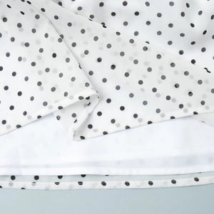 Detailed close-up of white polka dot chiffon dress hem with high-quality stitching